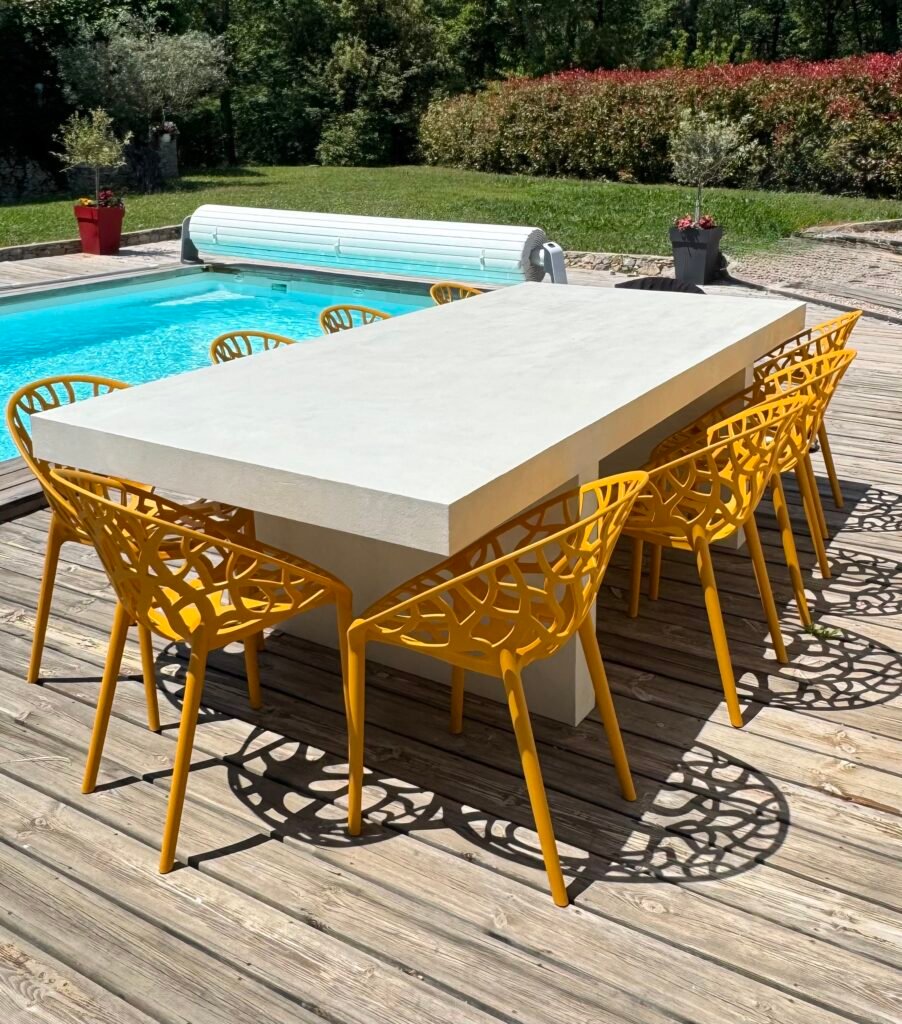 Grande table à aspect béton sur une terrasse au bord d'une piscine